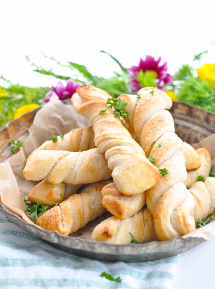 homemade breadsticks on a plate with flowers in the background