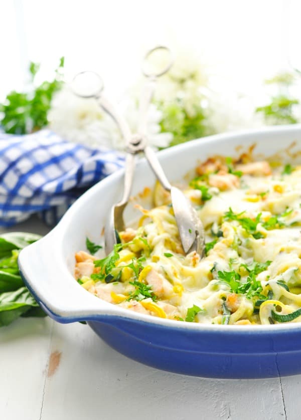 Chicken and zucchini noodles casserole in a blue baking dish with tongs
