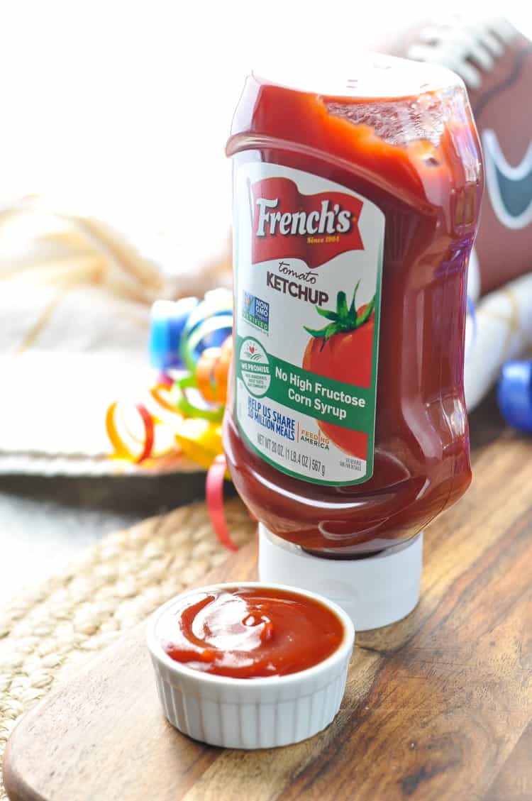 Bottle of French's Ketchup sitting on a wooden board used for dipping pretzel dogs into