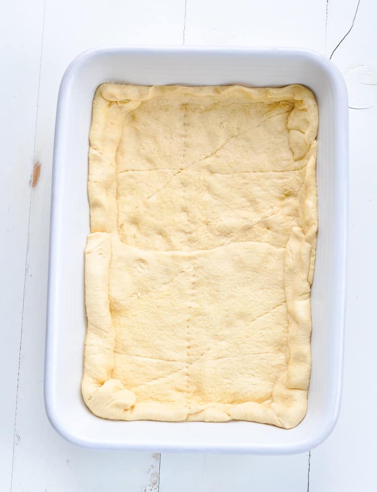 Pillsbury Crescent Roll dough in a large baking dish for making a breakfast casserole with bacon