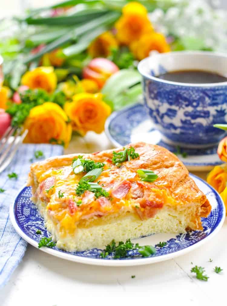Slice of a breakfast casserole with bacon on a blue and white plate with spring flowers