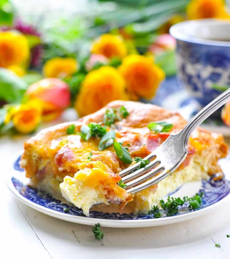An easy breakfast casserole with bacon and cheese on a small blue plate with a fork