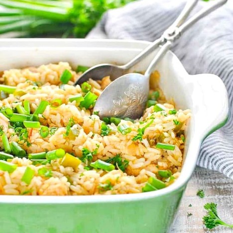 Front shot of a green casserole dish full of dirty rice and chicken