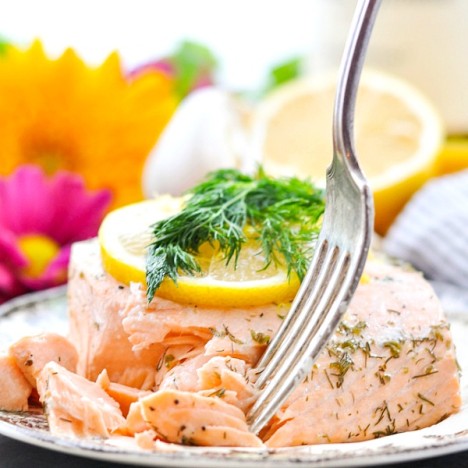 Close up shot of a fork taking a piece of poached salmon