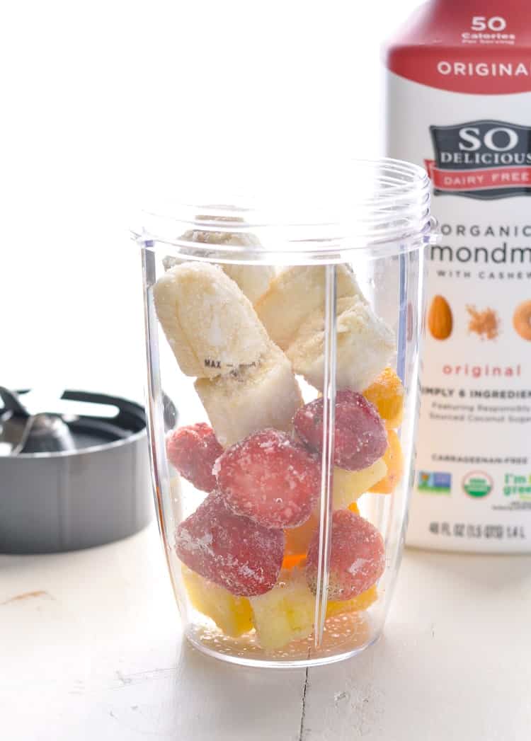 Frozen strawberries mangoes and bananas in blender ready to make a healthy strawberry smoothie