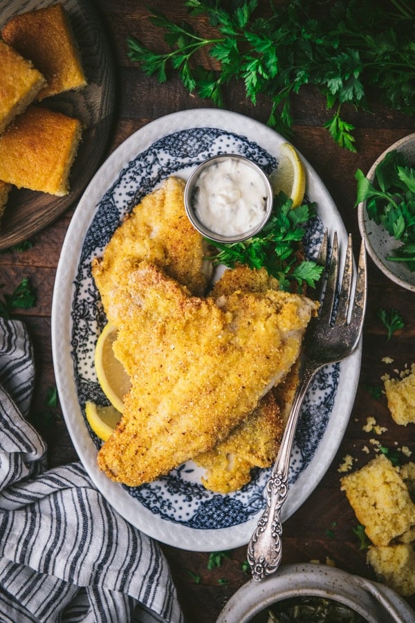 Overhead shot of crispy fried catfish with a side of cornbread and collard greens.