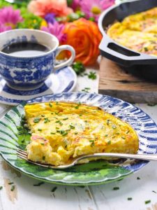 A slice of an easy frittata on a plate with a fork taking out a bite