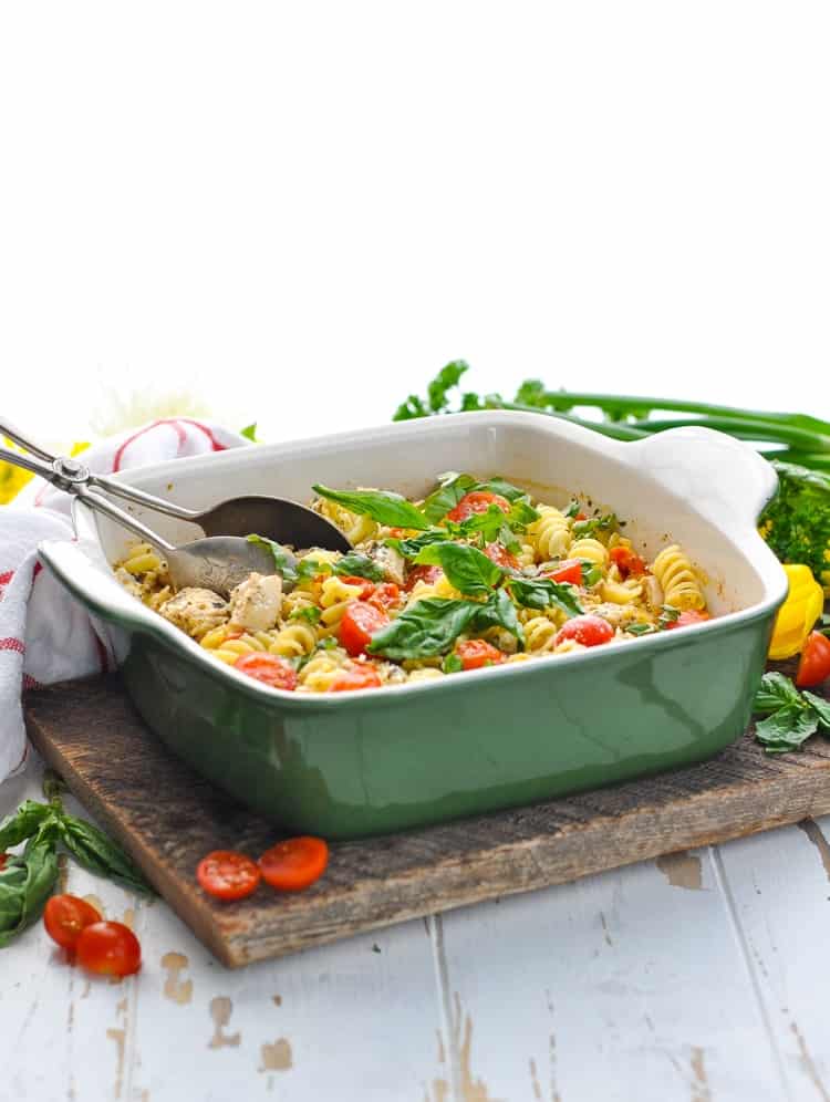 groene braadpan schotel vol kippenpesto pasta gegarneerd met verse tomaten en basilicum.
