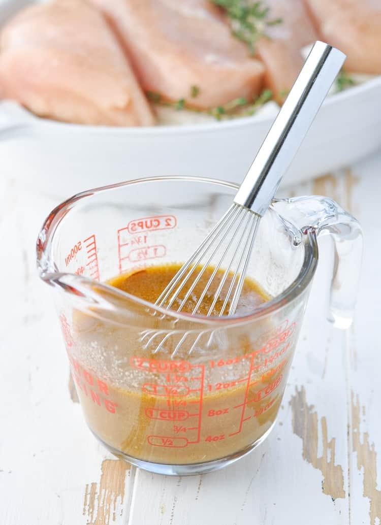 Sauce for Dump and Bake French Onion Chicken in a glass measuring cup with whisk