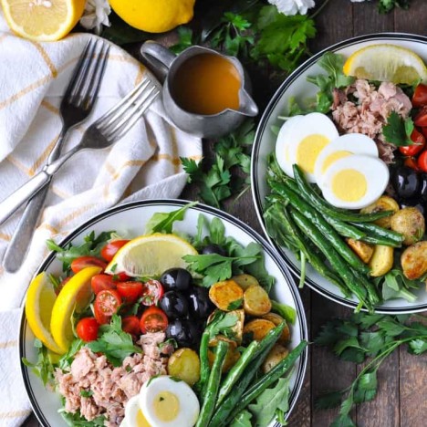 An overhead shot of two bowls filled with tuna nicoise salad