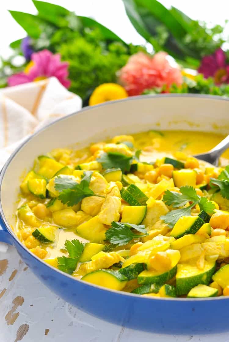 One skillet full of bright yellow Coconut Chicken Curry in a coconut milk broth with zucchini and garbanzo beans.