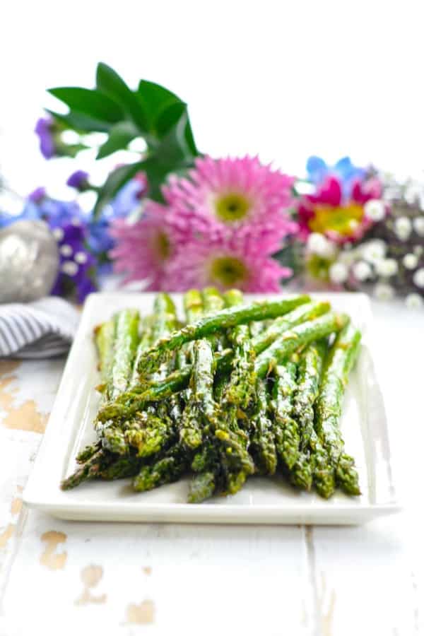 Front view of oven roasted asparagus stacked on a white serving tray