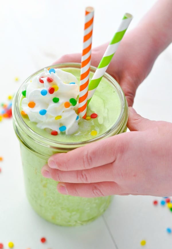 Child's hands holding a glass of Shamrock Shake