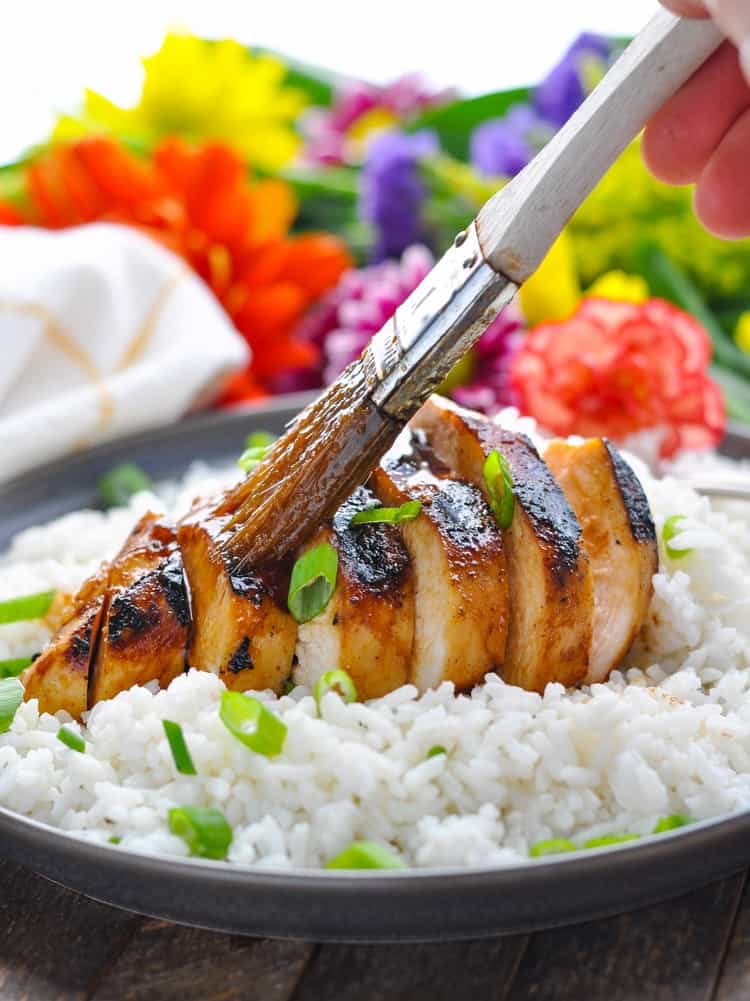 Basting a grilled chicken breast with an easy teriyaki sauce