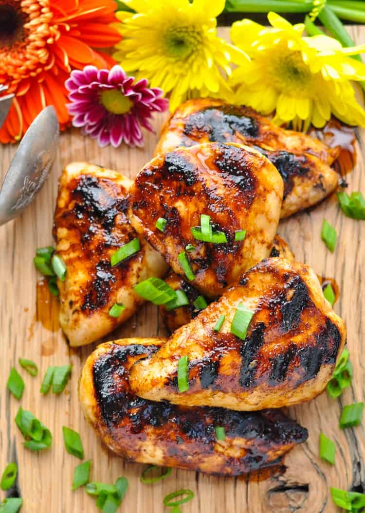 Overhead cutting board piled high with grilled chicken breasts in a teriyaki grilled chicken marinade