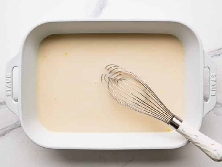Whisking the sauce and seasoning in the white baking dish.