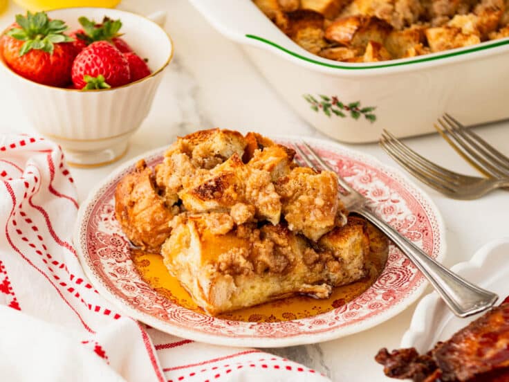 Horizontal side shot of French toast casserole on a plate with syrup.