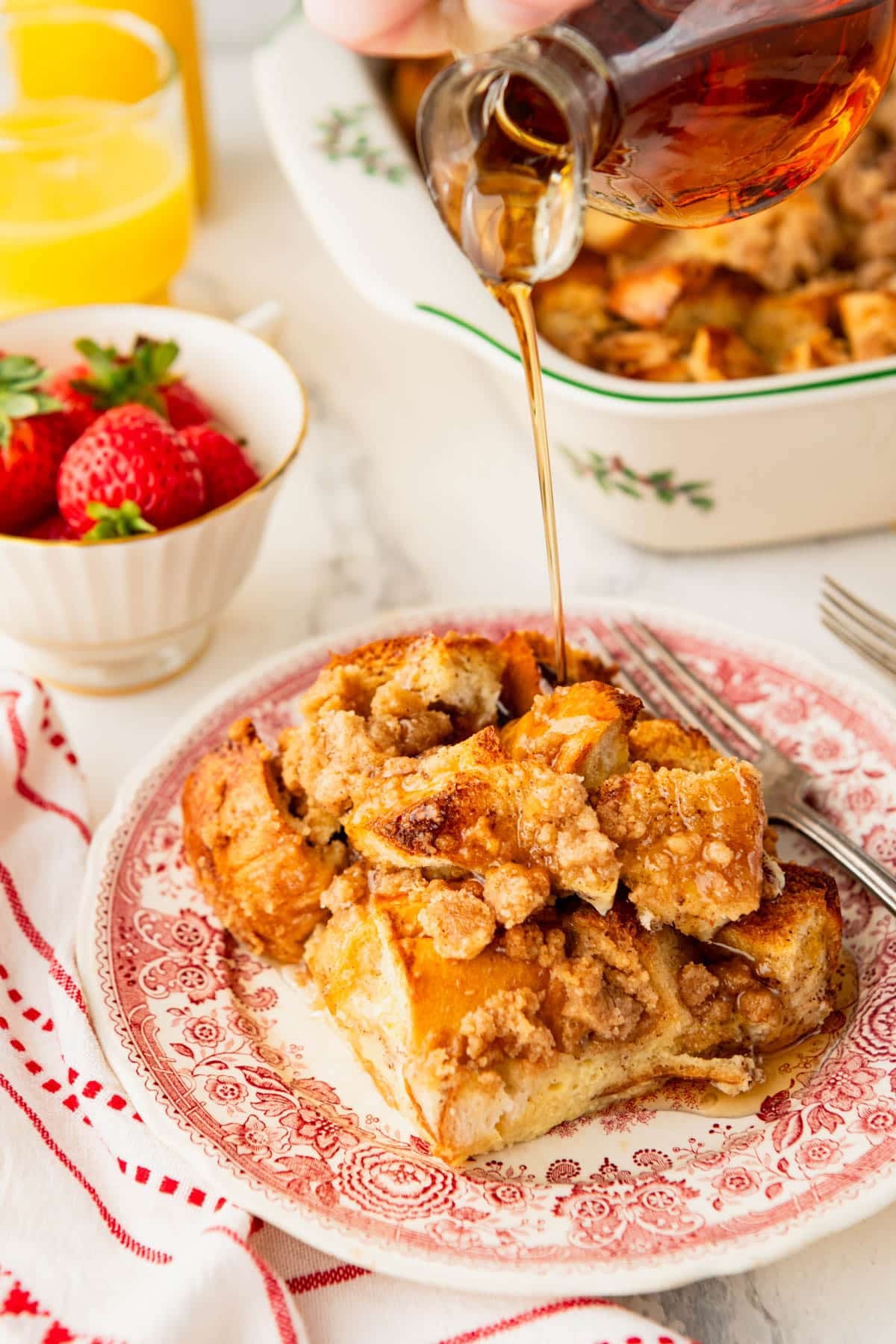 Pouring maple syrup on a slice of French toast casserole.
