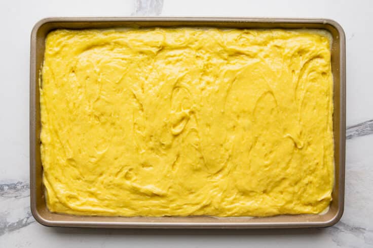 Lemon bar batter spread in a jelly roll pan.