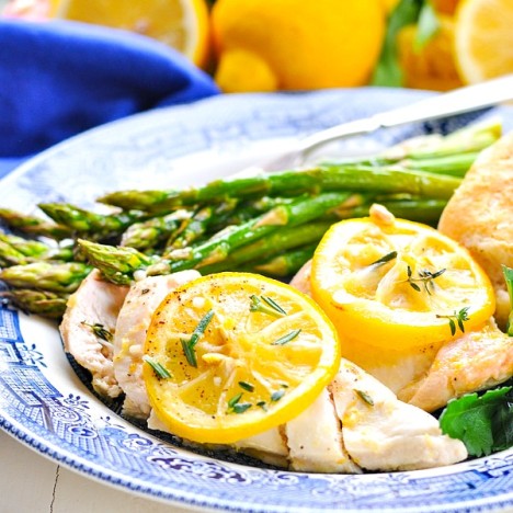 Sliced lemon chicken breast on a plate topped with lemon slices