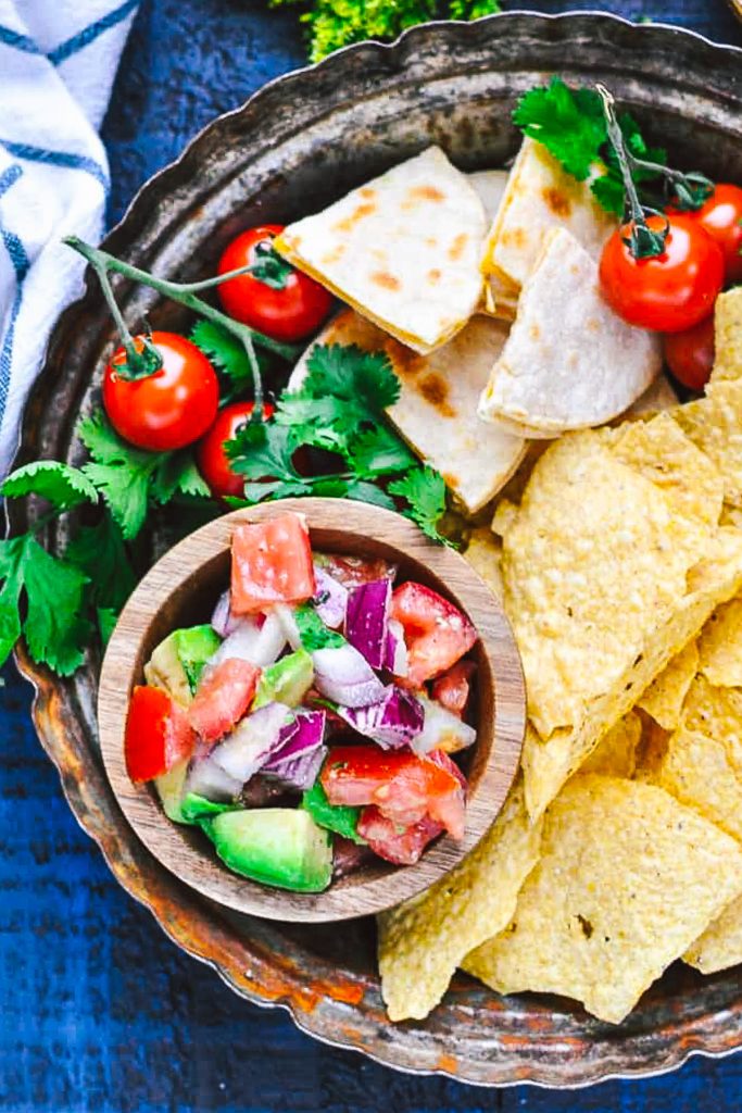 Overhead shot of a bowl of easy pico de gallo with a side of chips and quesadillas