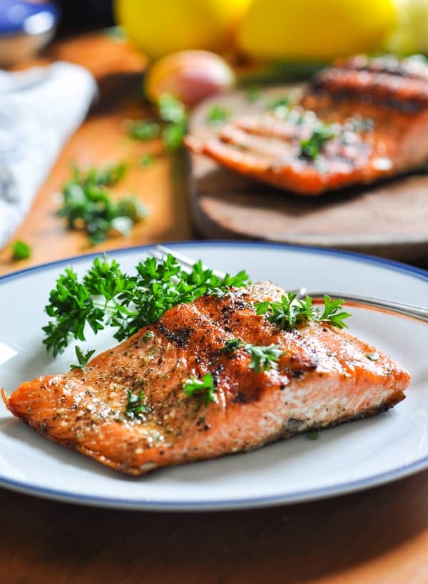 A beautiful piece of grilled salmon on a plate garnished with parsley.