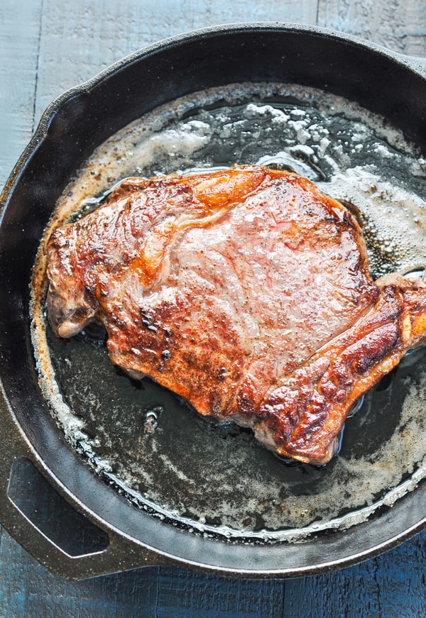 Seared ribeye steak in a skillet with garlic butter