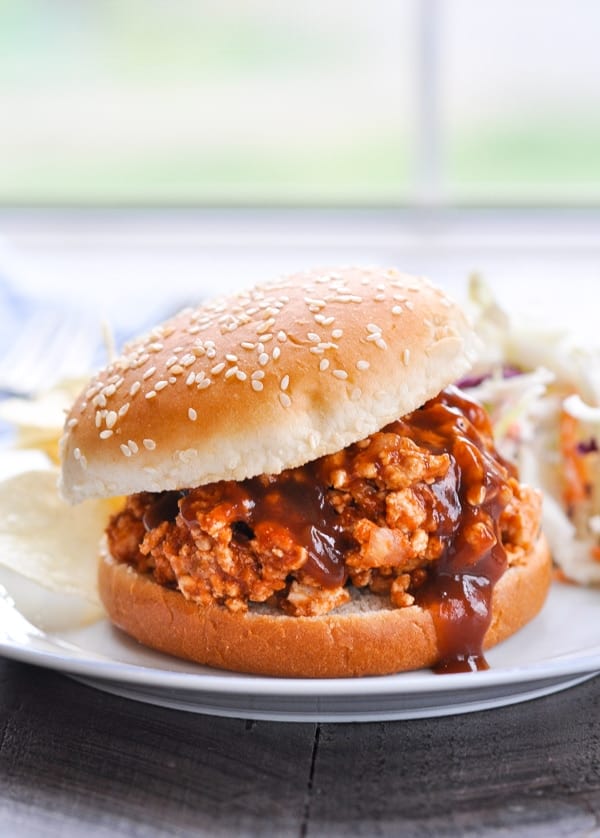Slow Cooker Turkey Sloppy Joe sandwich on a plate with coleslaw and potato chips.