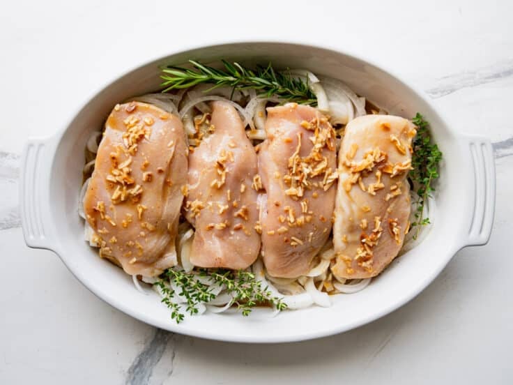 Pouring the sauce over the chicken in the dish before baking.