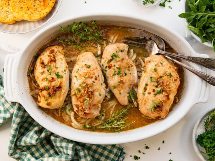 Horizontal overhead shot of a dish of baked French onion chicken garnished with fresh herbs.