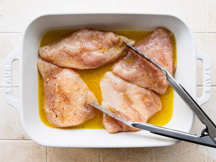 Adding the chicken to the sauce in the pan and tossing.