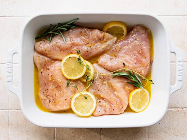 Chicken in a dish with lemon sauce before baking.
