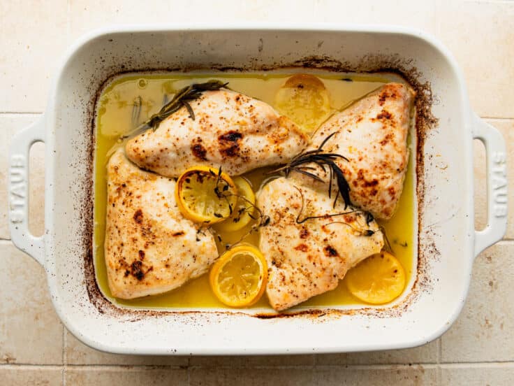 Baked lemon chicken in a white dish.