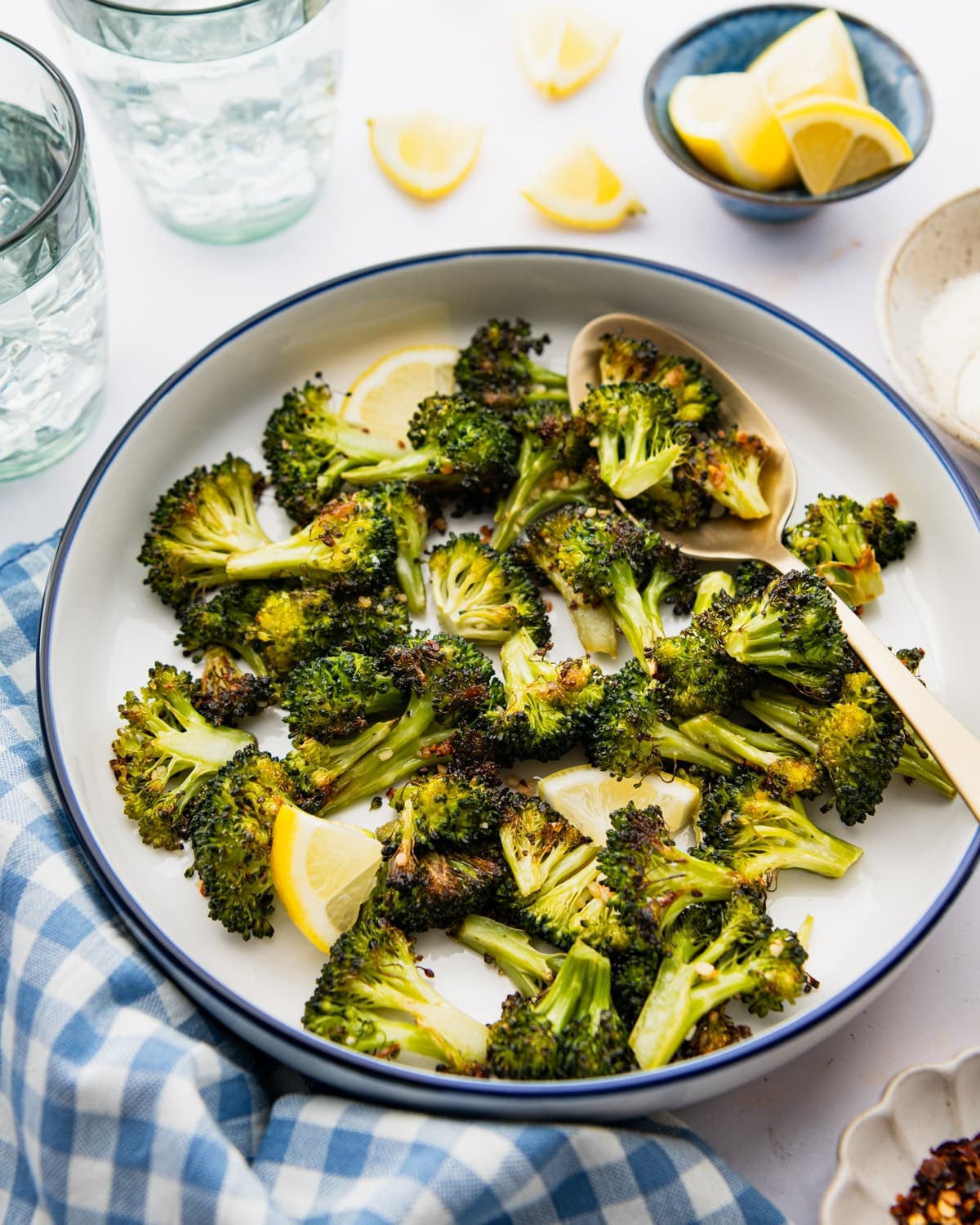 Baked broccoli and garlic in a bowl with a side of lemon.