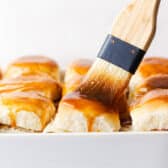 Brushing the tops of the rolls with the sweet garlic butter sauce.