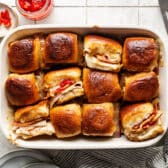 Horizontal overhead shot of a pan of baked hot brown sliders.