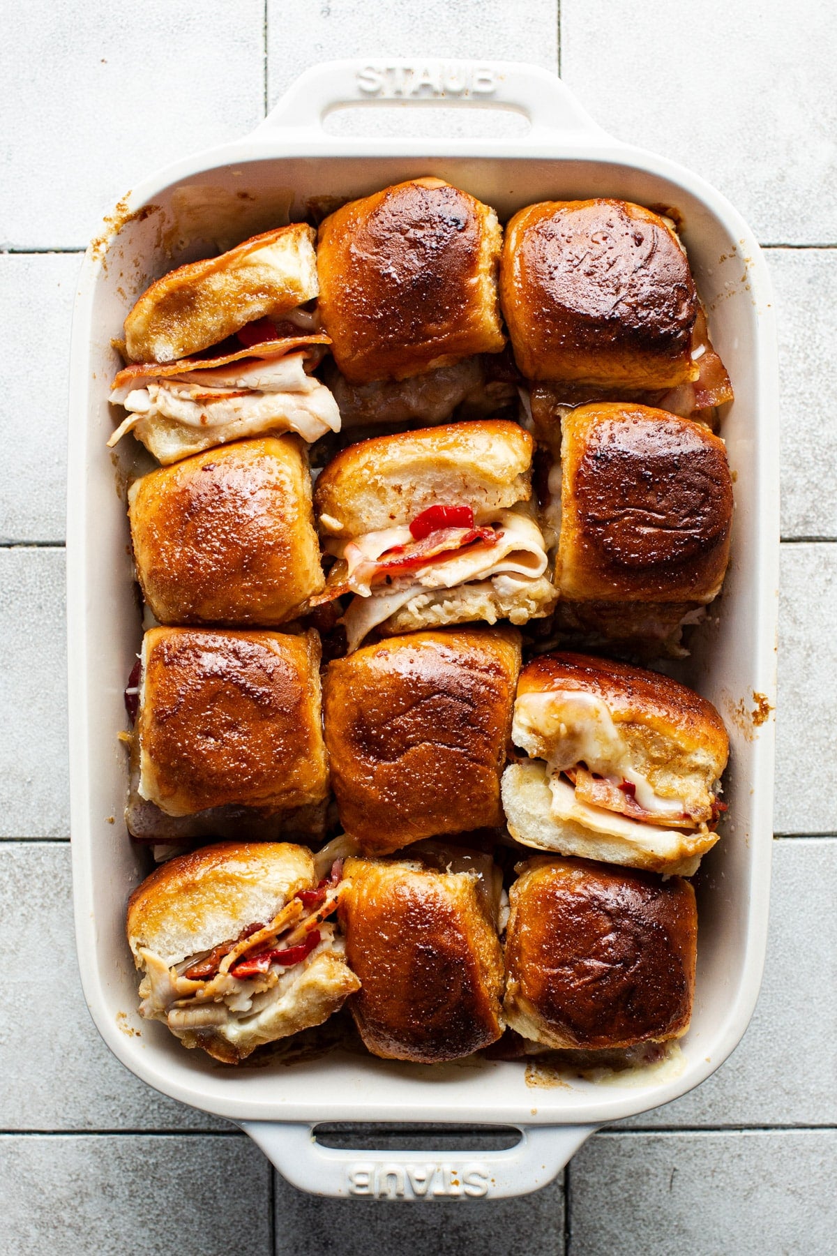 Overhead shot of a white baking dish full of Kentucky hot brown sliders.