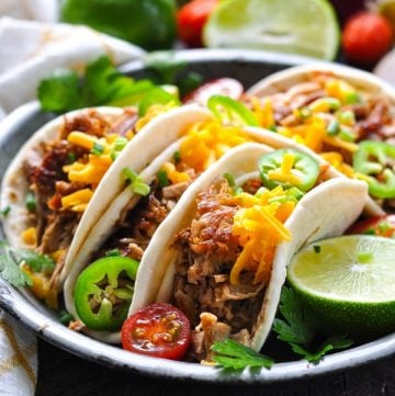 Close up side shot of tasty carnitas tacos on a metal plate
