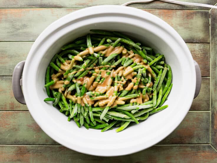 Pouring the sauce over the green beans in the Crock Pot.