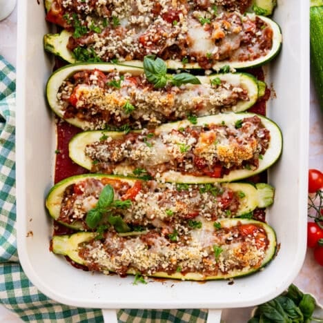 Square overhead shot of stuffed zucchini boats in a white baking dish.