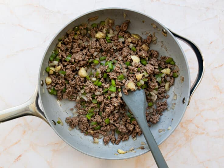 Browning ground beef and vegetables in a skillet.