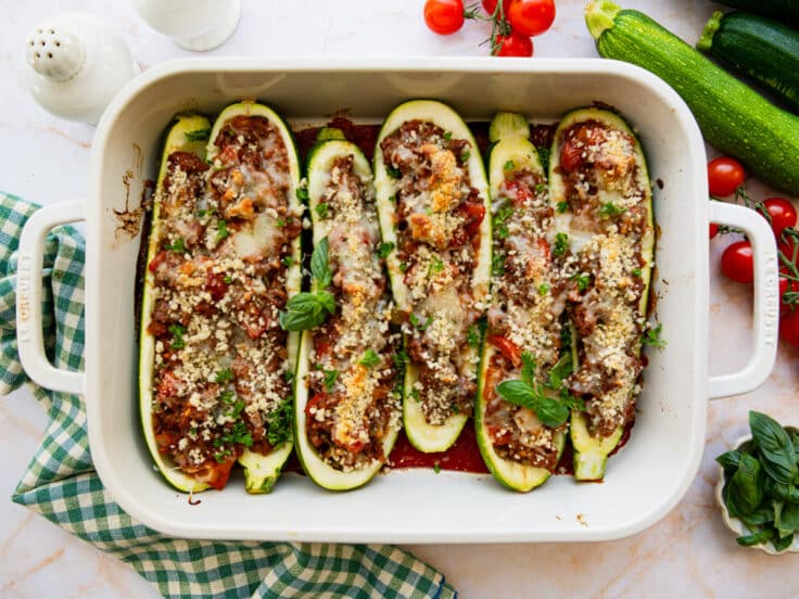 Horizontal overhead shot of stuffed zucchini boats in a white baking dish.