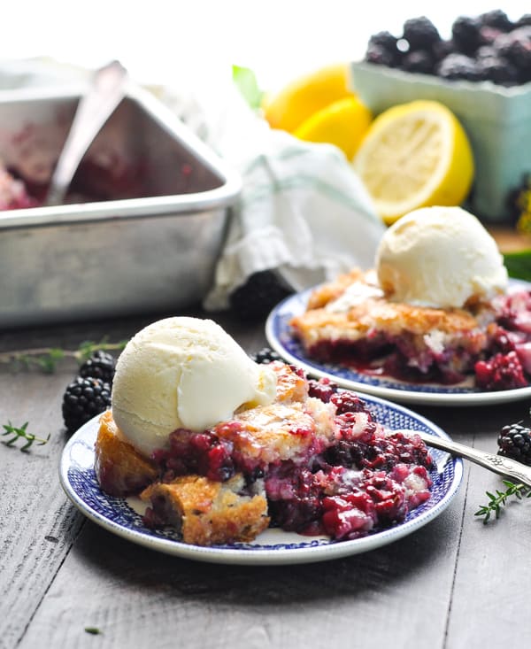 The best blackberry cobbler with vanilla ice cream on a small plate sitting on a wooden surface