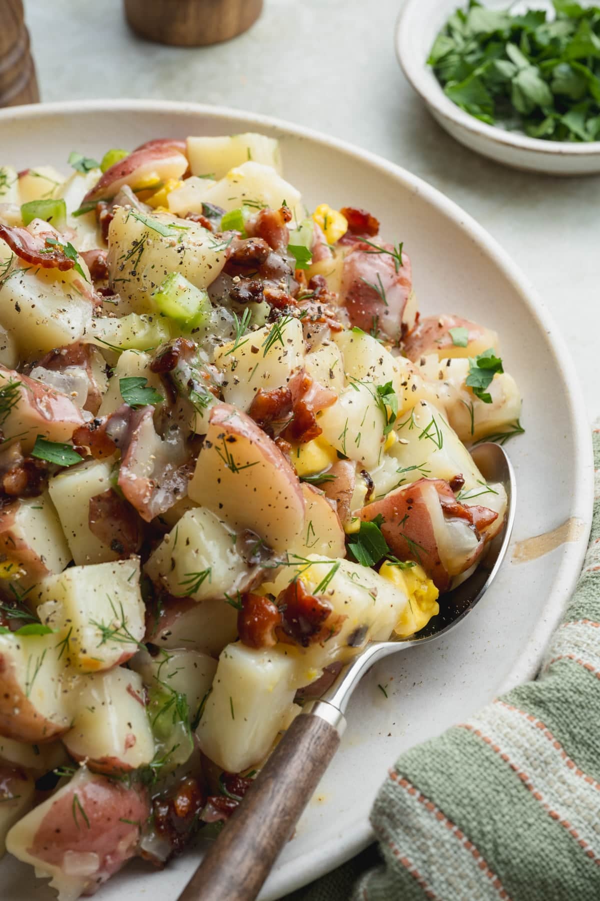 Close up side shot of a bowl of German potato salad with warm bacon dressing.