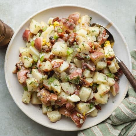 Square overhead shot of a bowl of German potato salad with warm bacon dressing.