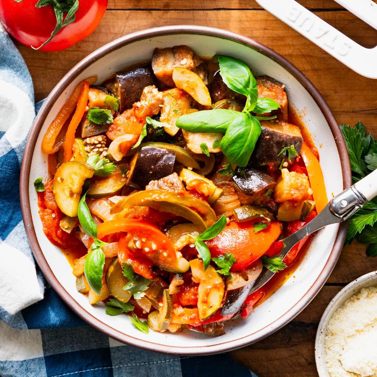 Square overhead shot of oven ratatouille in a bowl with fresh basil on top.