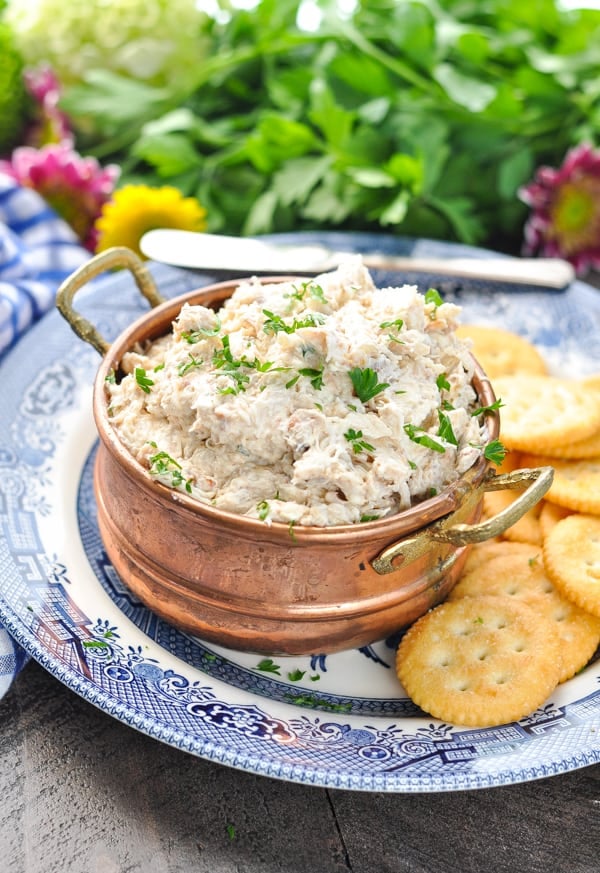 Copper bowl of cold crab dip on a plate with crackers
