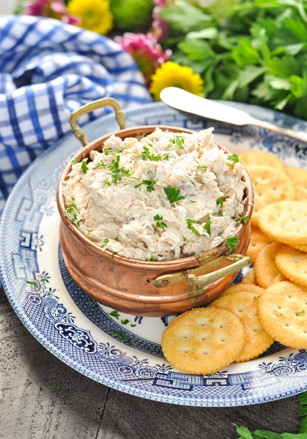 Copper bowl of crab dip garnished with fresh parsley