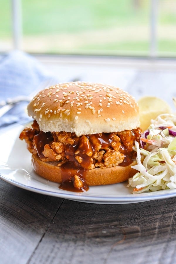 Slow Cooker Turkey Sloppy Joes on a sesame seed bun with coleslaw on the side