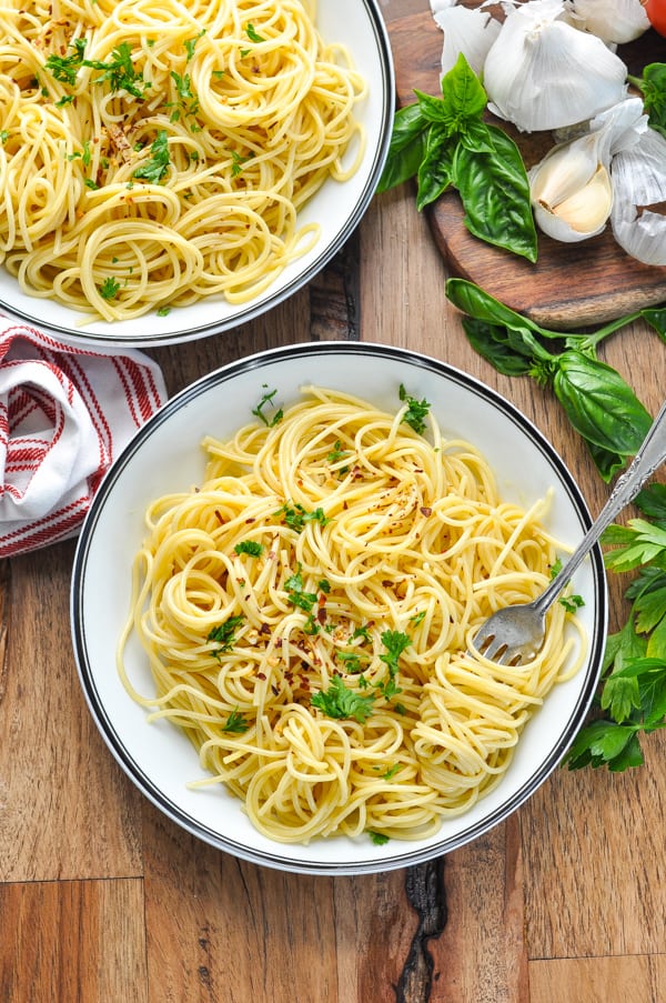 Overhead bowl of spaghetti aglio e olio recipe garnished with parsley and red pepper flakes